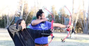 Teen and her mentor practicing archery