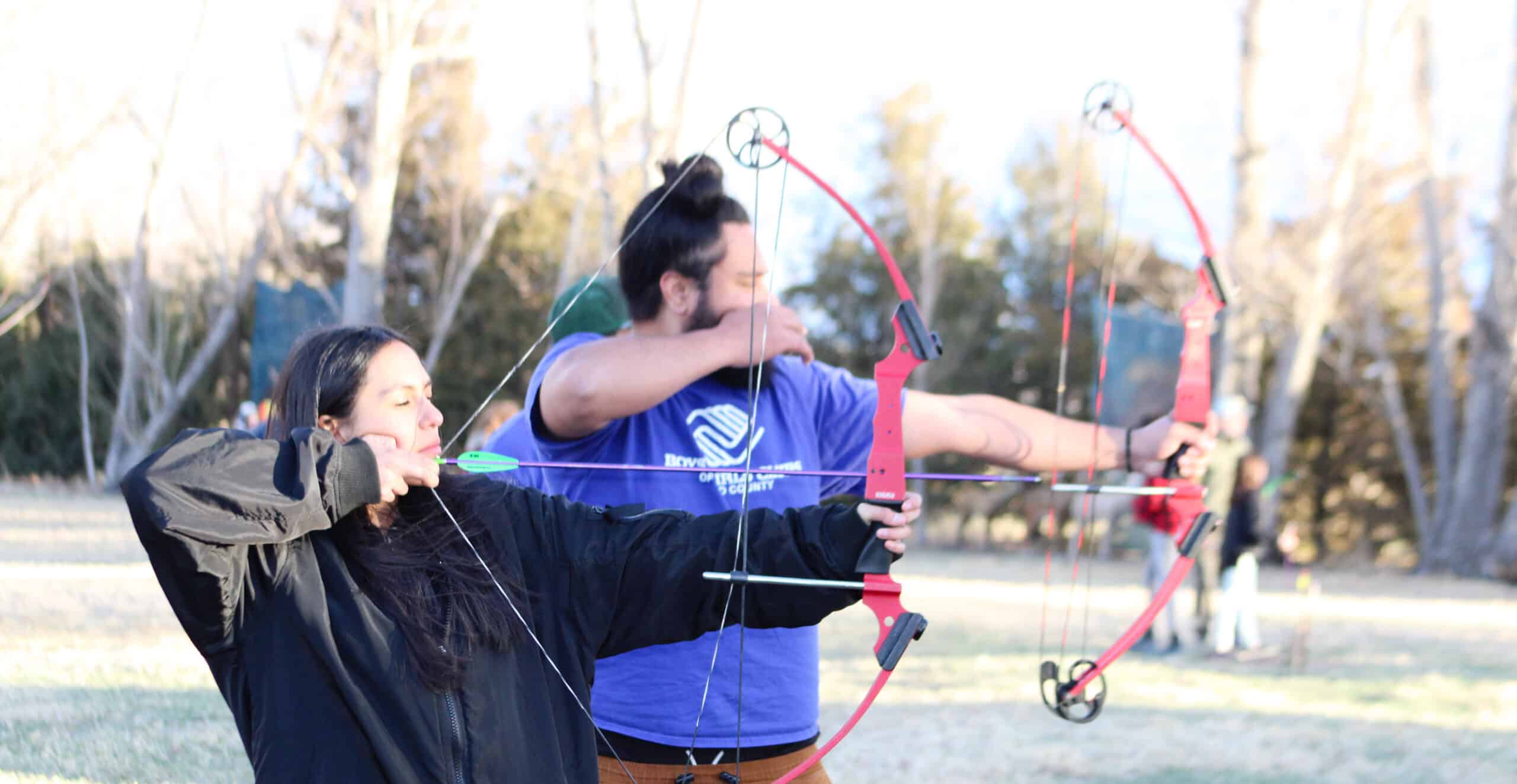 Teen and her mentor practicing archery